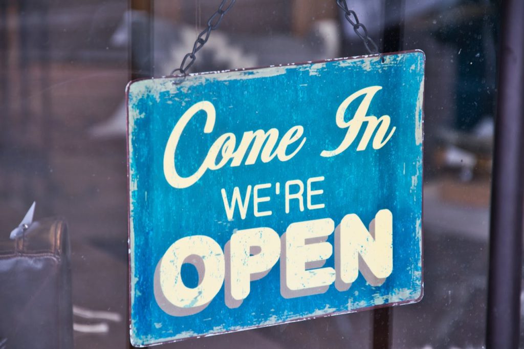 Retro blue open sign on a shop glass door inviting customers in.